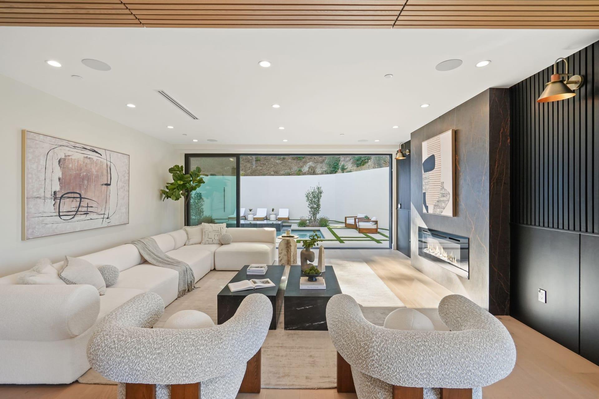 Staged living room with a white sectional and bouclé chairs facing a wide window onto the rear terrace