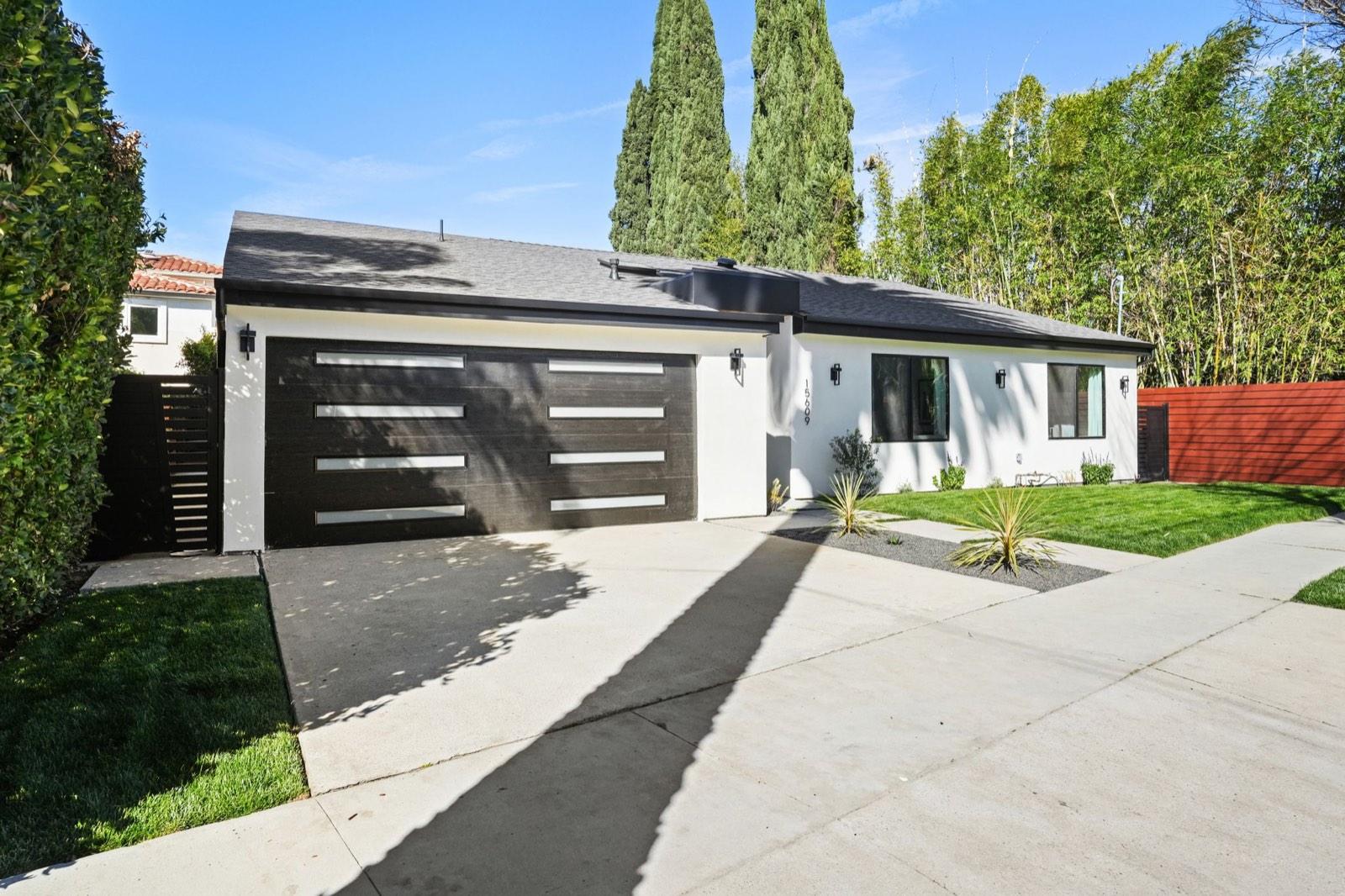 Full front elevation of the single-storey Encino home in daylight, with lawn and mature landscaping