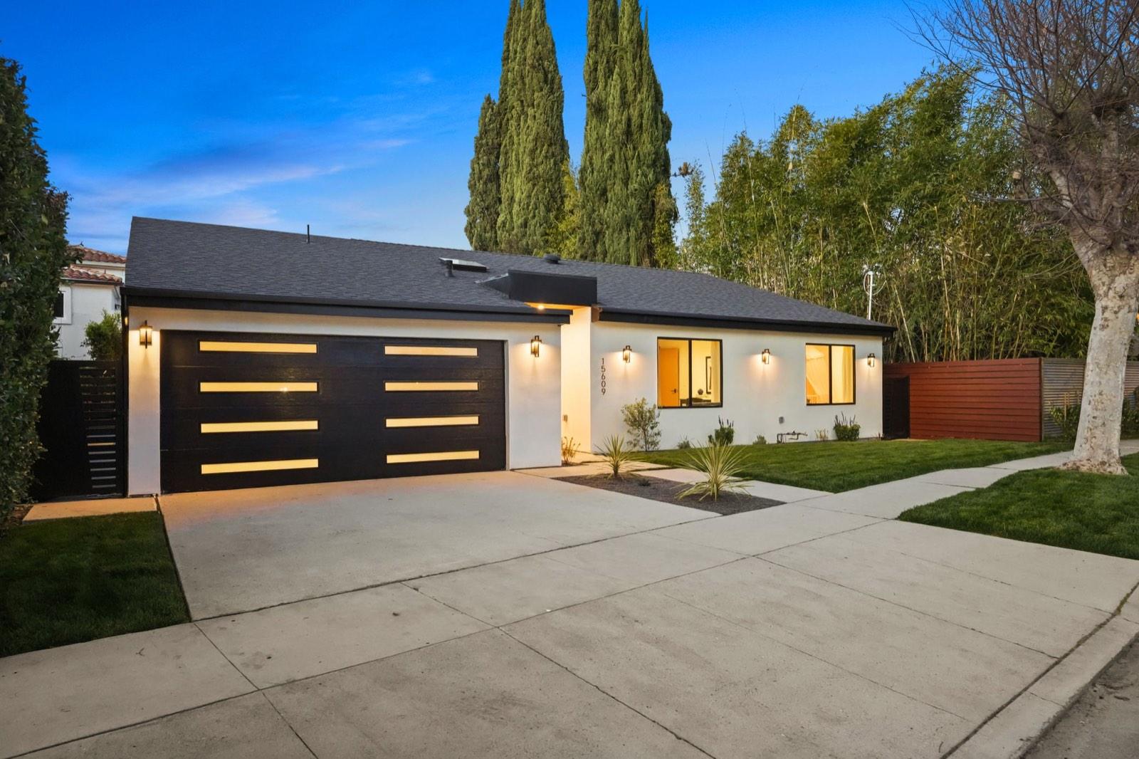 Front of the Encino residence at dusk showing the dark panelled garage doors and concrete driveway