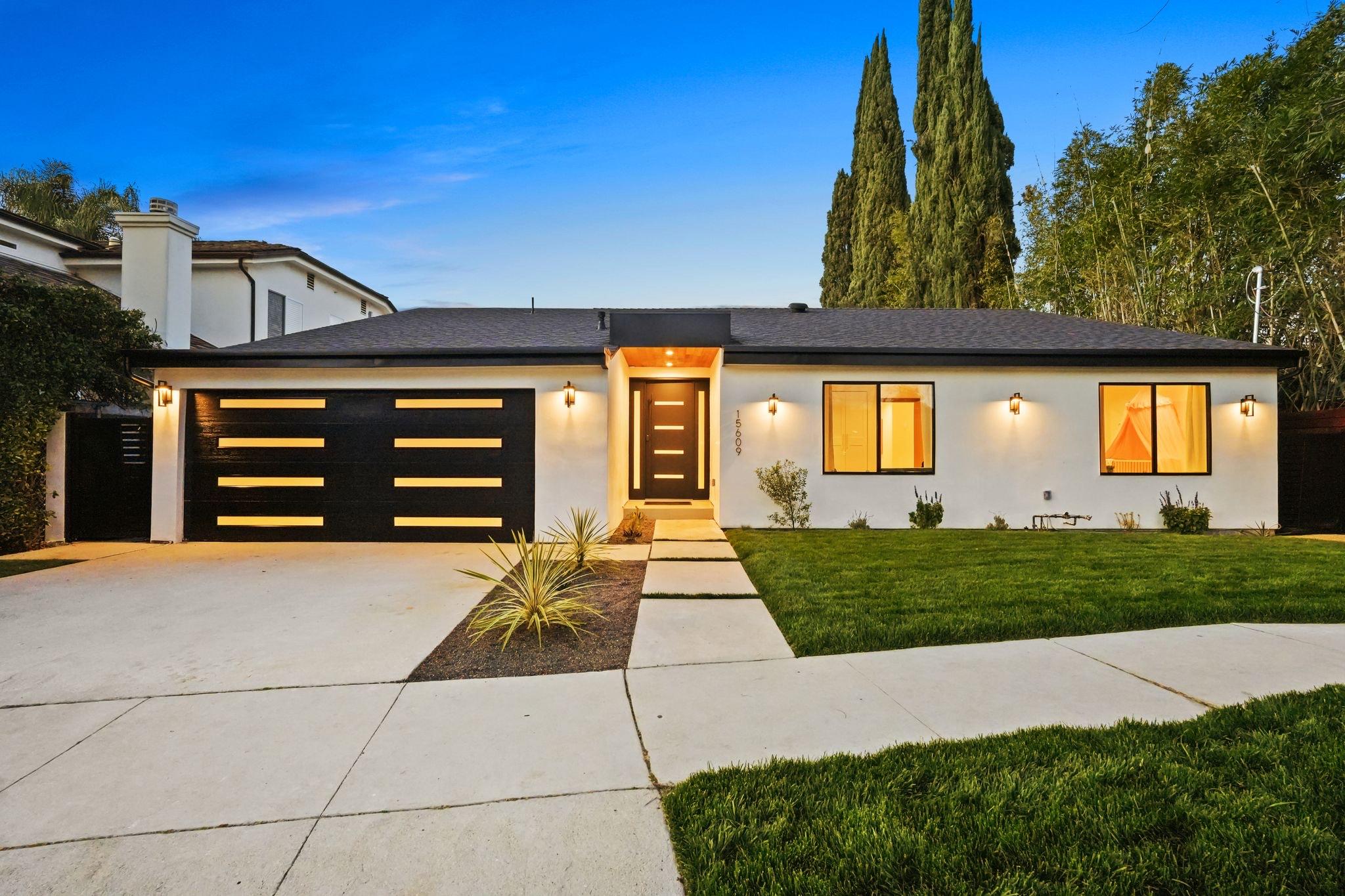 Front elevation of an Encino remodeled residence photographed at dusk, the entry and windows lit from within