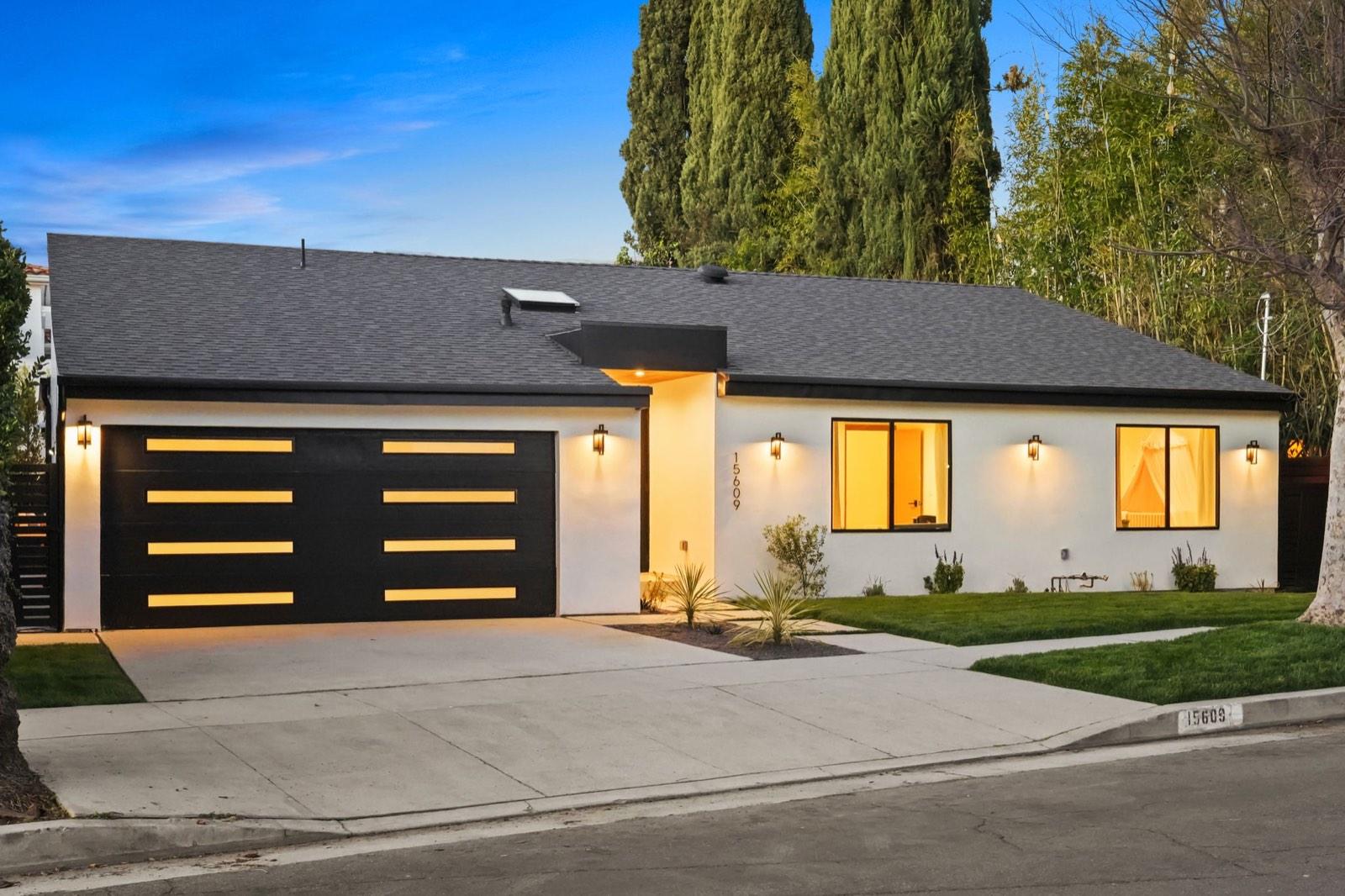 Street view of an Encino remodeled residence at dusk with the entry lit