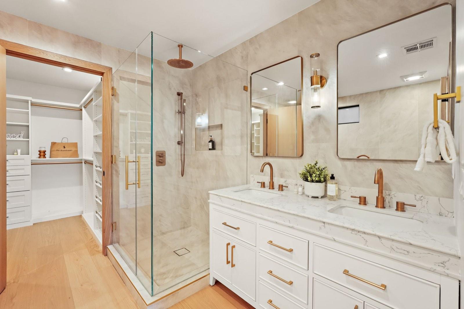 Primary bathroom double vanity with twin mirrors and a glazed shower