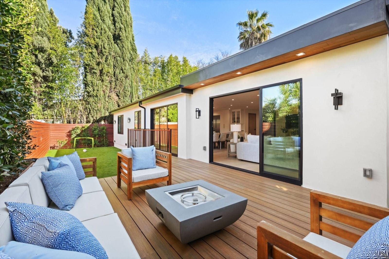 Timber rear deck with outdoor sofas and a concrete fire table beside the sliding doors of the house